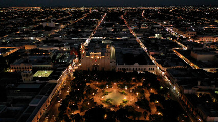 Aerial camera at night showing the Cathedral of Merida, Yucatan, Mexico and revealing the twinkling lights of the city. - obrazy, fototapety, plakaty