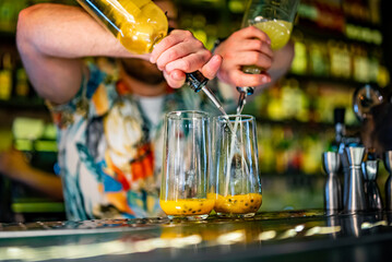 bartender making cocktail with passion fruit in a nightclub bar