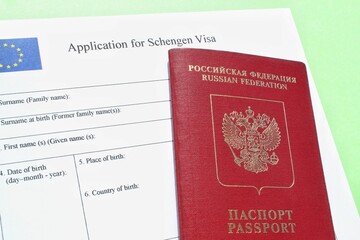 Passport of Russian Federation and application form for Schengen visa on green background. Prohibition and suspension of visas for tourists to travel to Europe, European Union, Baltic States concept