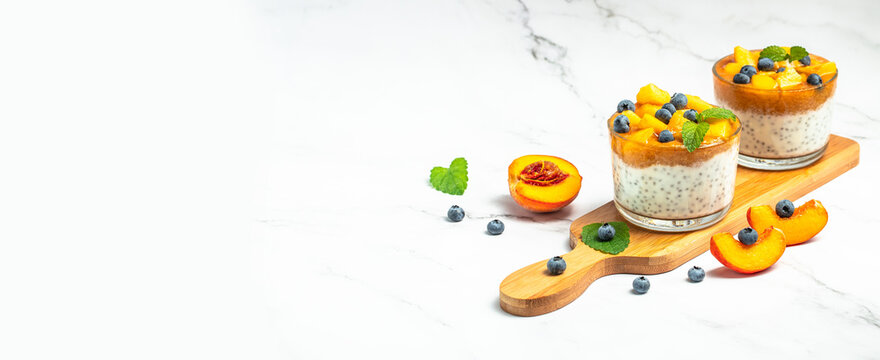 parfait dessert with peaches blueberry chia on a light background. Long banner format. top view