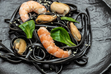 plate of black spaghetti with prawn prawn and mussels seafood. on dark background. Black spaghetti....