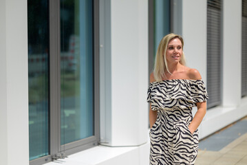 Happy blond woman standing at the entrance to a building