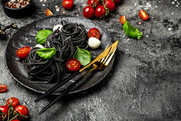 black pasta caprese salad tomatoes, mozzarella and green basil leaves. Clean eating, dieting, vegan...