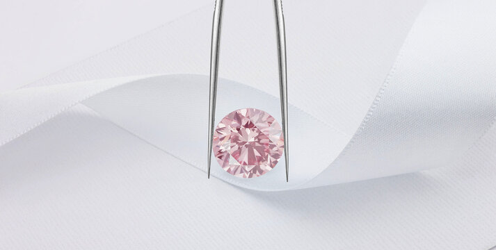 Pink Diamond in Tweezers on White Silk Background