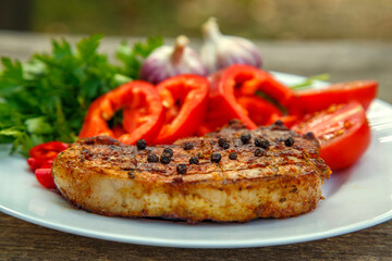 Meat steak cooked on the barbecue. Grilled fresh meat steak with spices and red pepper. Ready steak on the table with tomatoes and peppers. The concept of food, restaurants, traditional cuisine.