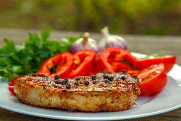 Meat steak cooked on the barbecue. Grilled fresh meat steak with spices and red pepper. Ready steak on the table with tomatoes and peppers. The concept of food, restaurants, traditional cuisine.