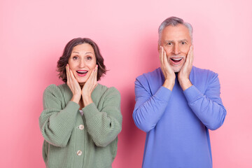 Portrait of two excited astonished people arms cheeks open mouth look camera isolated on pink color background