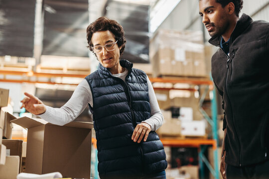 Female logistics manager training an employee in a warehouse