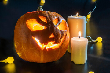 Halloween carved pumpkin. The smiling face of Jack O Lantern. Illuminated by a burning candle inside the scary Jack Lantern. Pumpkin decoration. Happy Halloween. yellow lanterns on black background