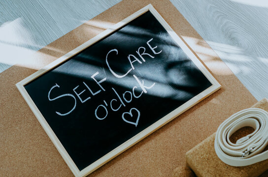Chalkboard with Self Care o'clock message on cork yoga mat with props