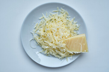 Plate with grated hard delicious cheese on a light background. Dairy. Concept: Italian cuisine, cheese, restaurant and food