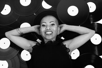Leisure and music concept. Portrait of Thai woman lying on black vinyl background with smile. Model...