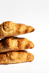 Fresh croissants in a stack on a white background. Homemade cakes, fresh bread from the bakery