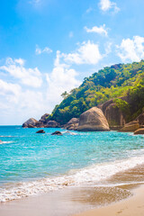 Vertical tropical landscape. Sea with a rocky shore and a mountain on a sunny day on a tropical island. Travel and tourism