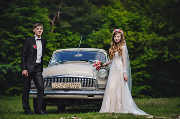 Happy bride and groom, newlywed wedding couple near a retro car on a country for honeymoon after the ceremony. The best day and marriage. Just married.