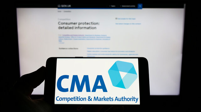 Stuttgart, Germany - 08-27-2022: Person holding cellphone with logo of British Competition and Markets Authority (CMA) on screen in front of webpage. Focus on phone display.