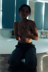 Beautiful young woman with amputee arm and scars from burn on her body poses topless.