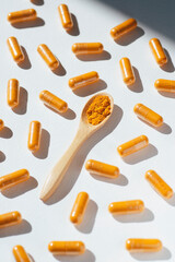 Turmeric plus black pepper extract gelatin capsule close up with wooden spoon. Herbal supplement organic curcumin. Supports antioxidant health