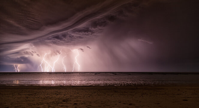 Orage la nuit au-dessus de l'oc&eacute;an avec &eacute;clairs multiples &eacute;clairant les bouchots de moules et la plage. La Gu&eacute;rini&egrave;re, &icirc;le de Noirmoutier 