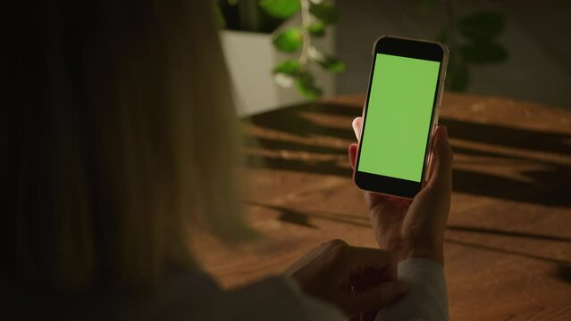 Handheld close up woman holding smart phone with green screen chroma key and doing a single swipe