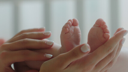 Pretty cute baby legs in the morning routine young mother touching carefully the little legs of her baby