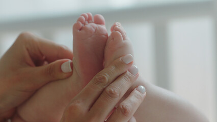 Childhood concept in front of the camera pretty baby legs mommy playing carefully holding the baby legs in her hands