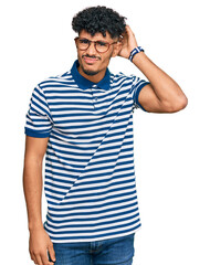 Young arab man wearing casual clothes and glasses confuse and wonder about question. uncertain with...