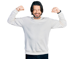 Fototapeta premium Middle age caucasian man wearing casual clothes showing arms muscles smiling proud. fitness concept.