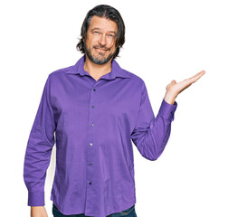 Middle age handsome man wearing business shirt smiling cheerful presenting and pointing with palm of hand looking at the camera.