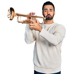 Young hispanic man with beard playing trumpet depressed and worry for distress, crying angry and...