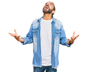 Attractive man with long hair and beard wearing casual denim jacket crazy and mad shouting and yelling with aggressive expression and arms raised. frustration concept.