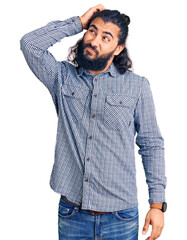 Young arab man wearing casual clothes confuse and wondering about question. uncertain with doubt,...