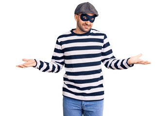 Young handsome man wearing burglar mask smiling showing both hands open palms, presenting and advertising comparison and balance