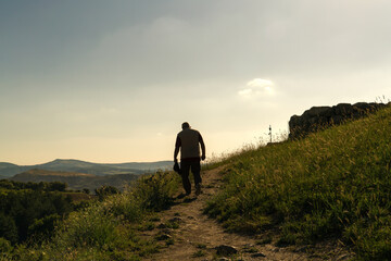 Silhouette of rear view of old man walking on hill in evening