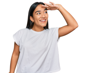Young asian woman wearing casual white t shirt very happy and smiling looking far away with hand over head. searching concept.