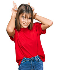 Obraz na płótnie Canvas Teenager caucasian girl wearing casual red t shirt posing funny and crazy with fingers on head as bunny ears, smiling cheerful