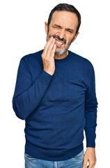 Middle age hispanic man wearing casual clothes touching mouth with hand with painful expression because of toothache or dental illness on teeth. dentist