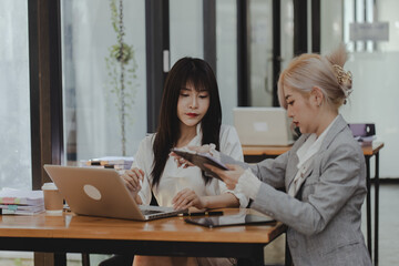 Two asian businesswoman talking together sitting in office, Startup and business project concept. 