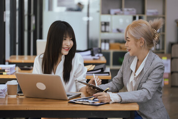 Happy smiling business woman Working on laptop computer with paperwork at desk in a modern office,  business finance technology concept.
