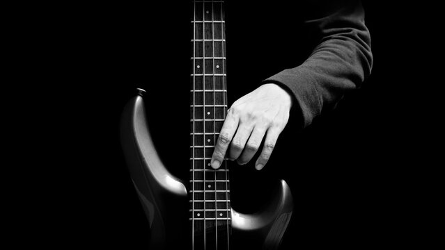 black and white musician hands posing on electric bass guitar, isolated on black. music concept