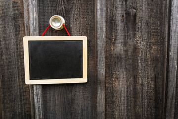 A small graphite note board on a wooden background, a note board, a frame hanging on a pen, a place for an inscription.
