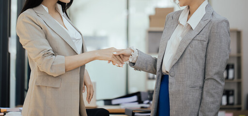 Businesswoman partnership handshake concept. Two young asian business professionals celebrating...