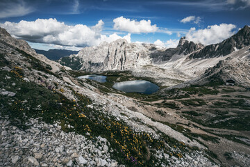 mountain landscape with clouds and small alpine lake in the dolomites on a summer day