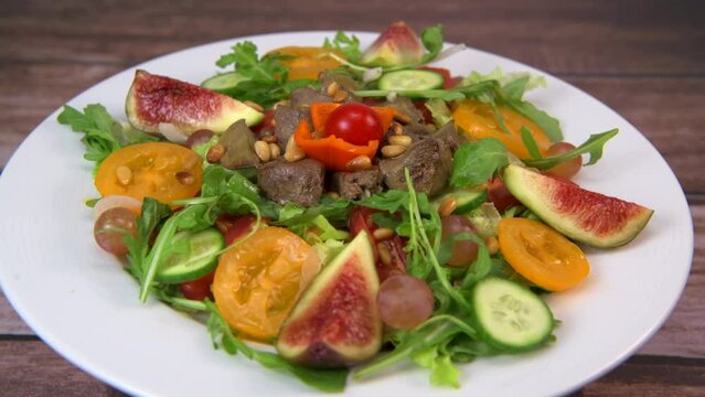 Recipe for fried chicken liver and gizzards with salad and tomatoes, cucumber, figs, grapes on a white plate, High quality video