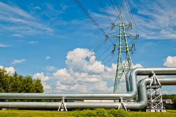 pipeline and power line support, in the photo pipeline and power line tower close-up against the background of blue sky and clouds