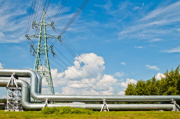 pipeline and power line support, in the photo pipeline and power line tower close-up against the background of blue sky and clouds