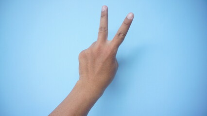 Peace sign gesture made by child on blue background. World peace concept
