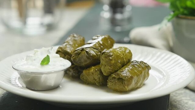 Serving the freshly prepared Dolmas - stuffed grape leaves.
