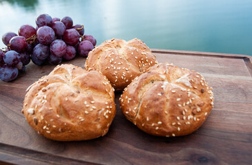 Buns and a grape on a cutting board above the river.