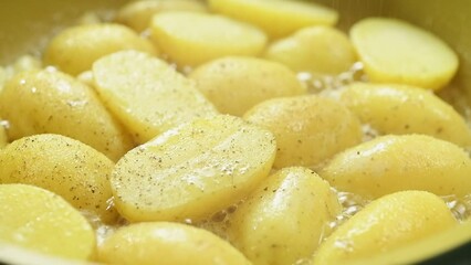The cook sprinkles the chopped potatoes with black pepper while the potatoes are frying in the pan.
